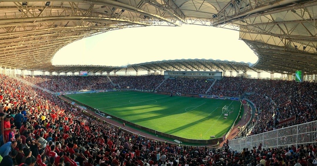 Gefülltes Fußballstadion mit grünem Rasen unter weitgehend geschlossenem Dach