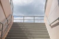 Breite Betontreppe mit Handläufen führt unter freiem Himmel nach oben