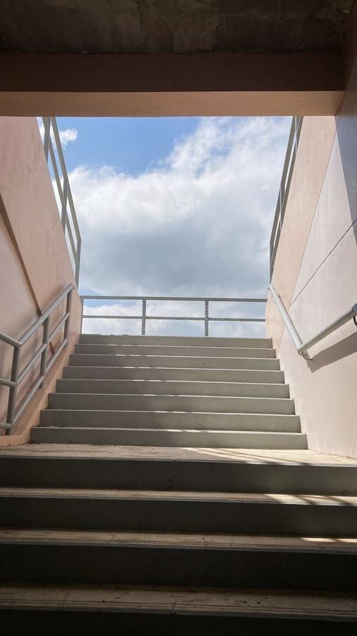 Breite Betontreppe mit Handläufen führt unter freiem Himmel nach oben